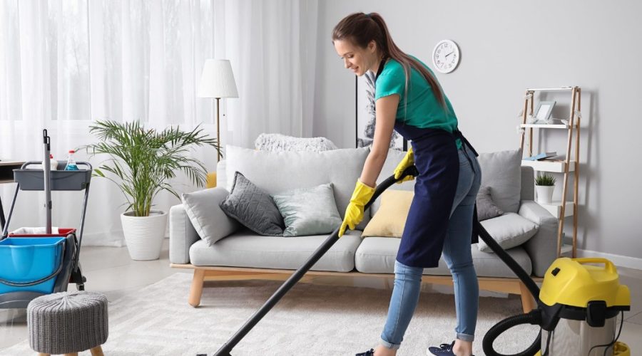 A professional cleaner vacuuming a living room carpet as part of Residential Cleaning Services, ensuring a spotless and fresh home environment.