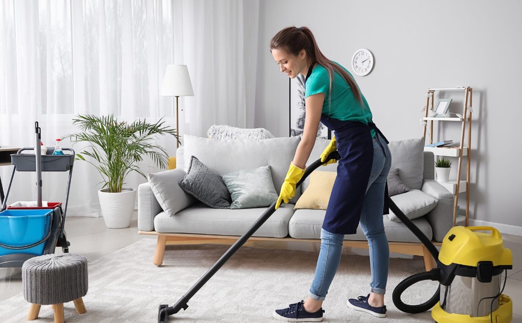 A professional cleaner vacuuming a living room carpet as part of Residential Cleaning Services, ensuring a spotless and fresh home environment.