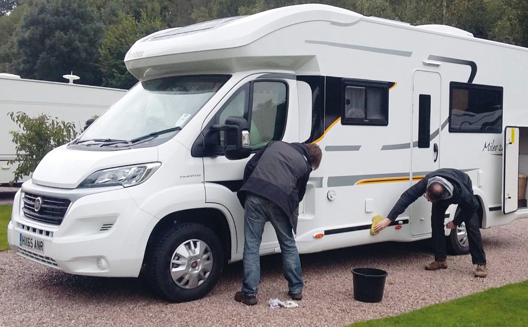 Two individuals carefully wash an RV, highlighting the attention to detail of Specialty RV Cleaning Services for maintaining the vehicle’s appearance and condition.